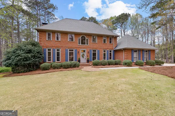 a front view of a house with a yard and trees