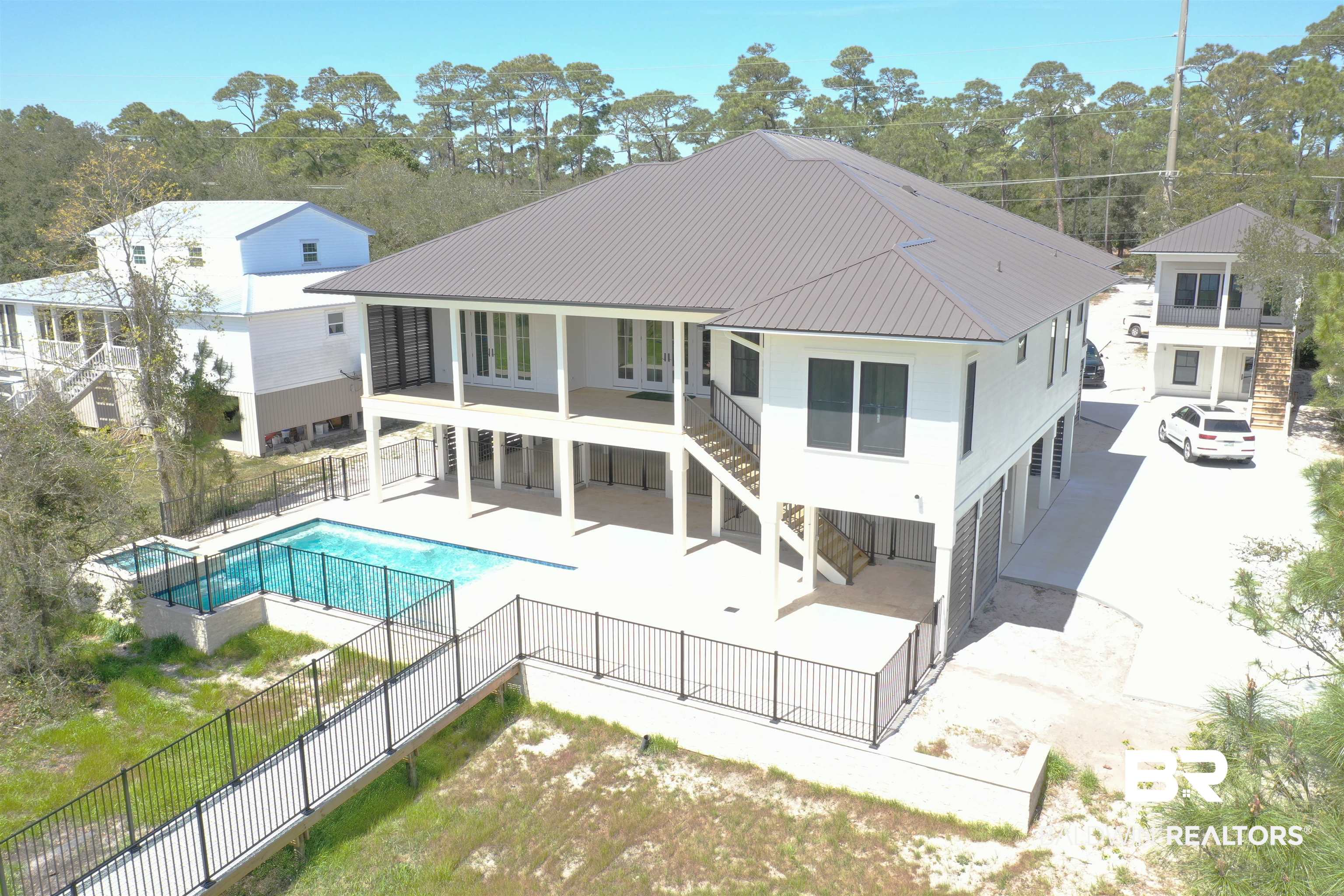 14686 State Highway Gulf Shores, AL 36542 - Photo 1 of 44 Rear view of house with stairway, metal roof, a fenced backyard, and a patio area