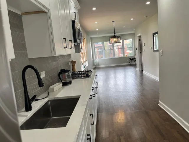 a kitchen with granite countertop a stove a sink a refrigerator and wooden floor