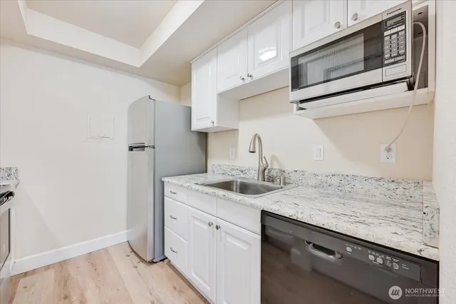 a kitchen with stainless steel appliances granite countertop a sink and a refrigerator