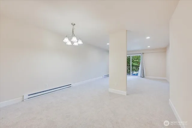 an empty room with a kitchen space and a chandelier