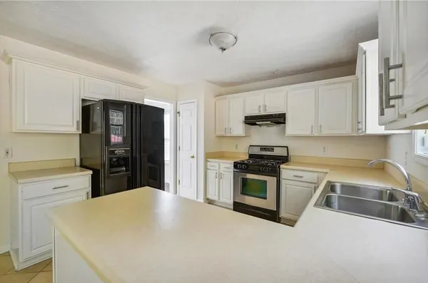 a kitchen with refrigerator a stove a sink and a white cabinets