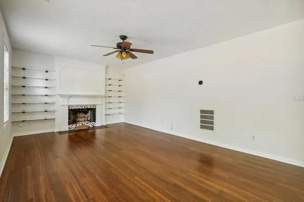 a view of a livingroom with a fireplace a ceiling fan and window