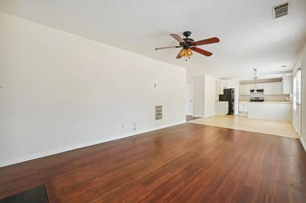 an empty room with wooden floor a ceiling fan and window
