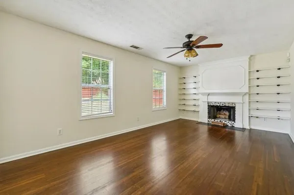 an empty room with windows fireplace and wooden floor