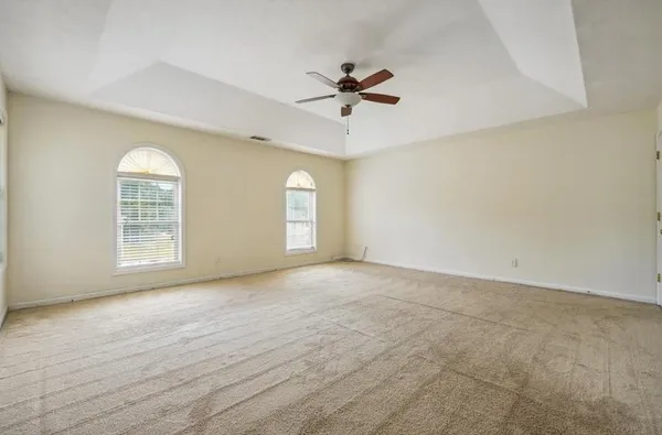 an empty room with windows and fan