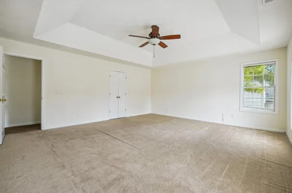 an empty room with windows and fan