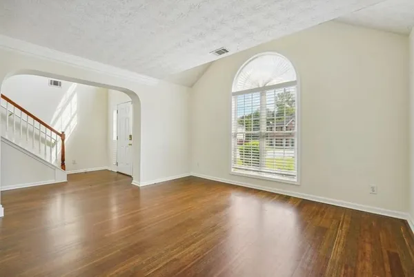 a view of an empty room with wooden floor and a window