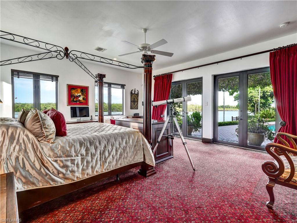 2535 Tarpon Road Naples, FL 34102 - Photo 21 of 50 Spacious room featuring red patterned carpeting, a ceiling fan, recessed lighting, a large wall mirror with a carved wood frame, and a dark wood four-poster bed