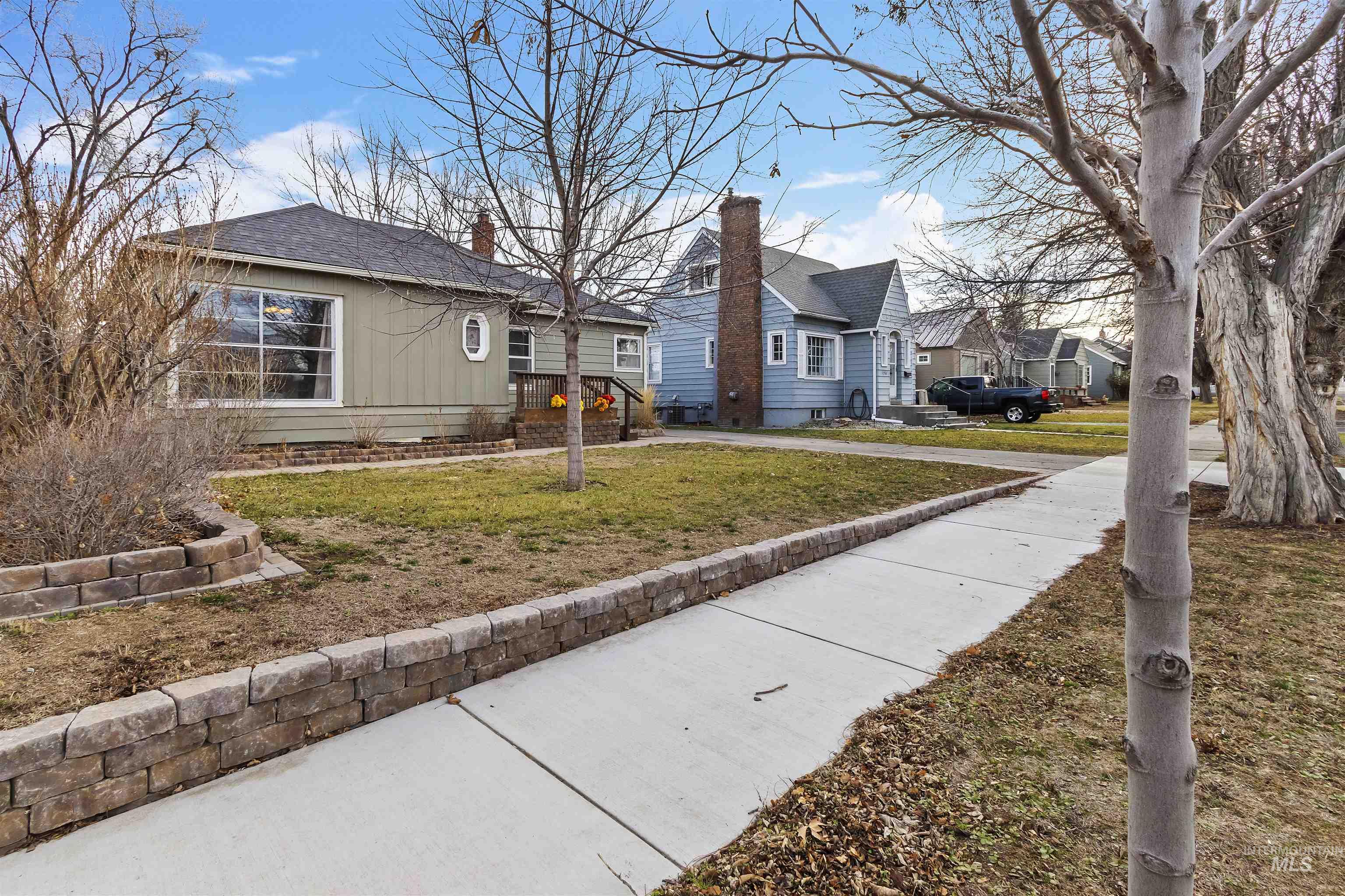 184 Taylor Street Twin Falls, ID 83301 - Photo 3 of 23 View of side of home featuring a yard, a shingled roof, a residential view, and a chimney