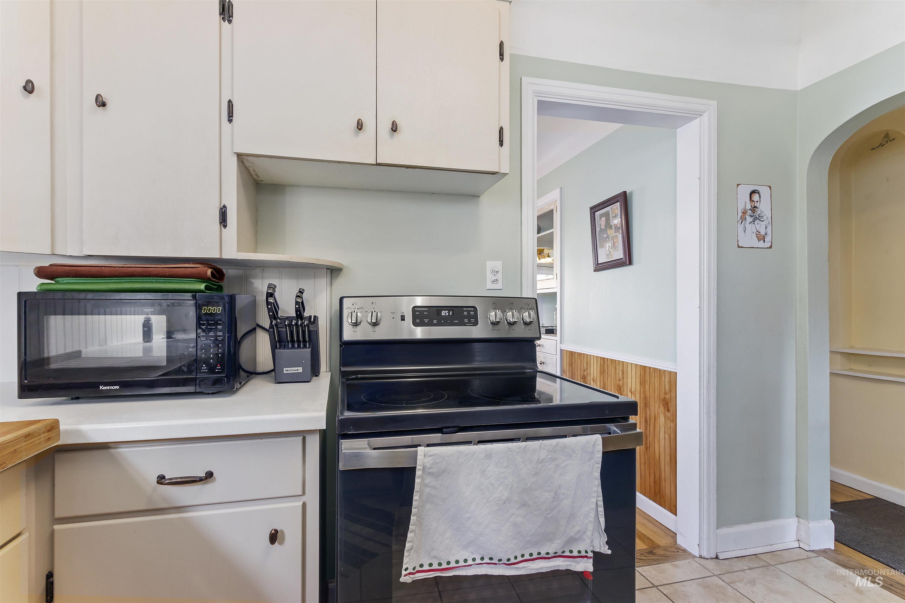184 Taylor Street Twin Falls, ID 83301 - Photo 9 of 23 Kitchen featuring stainless steel electric range, light countertops, black microwave, a wainscoted wall, and arched walkways