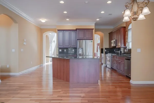 a kitchen with kitchen island granite countertop wooden floors stainless steel appliances a sink and a window