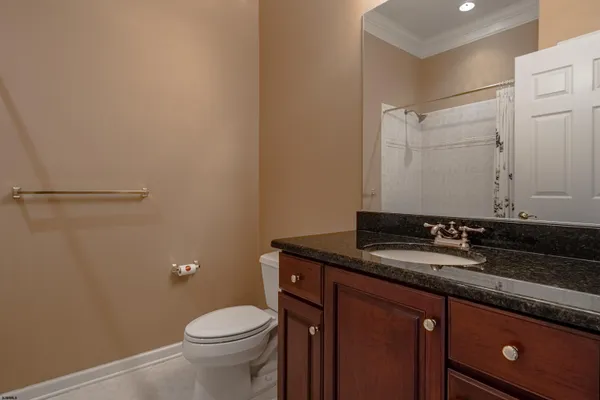 a bathroom with a granite countertop sink a toilet and a mirror