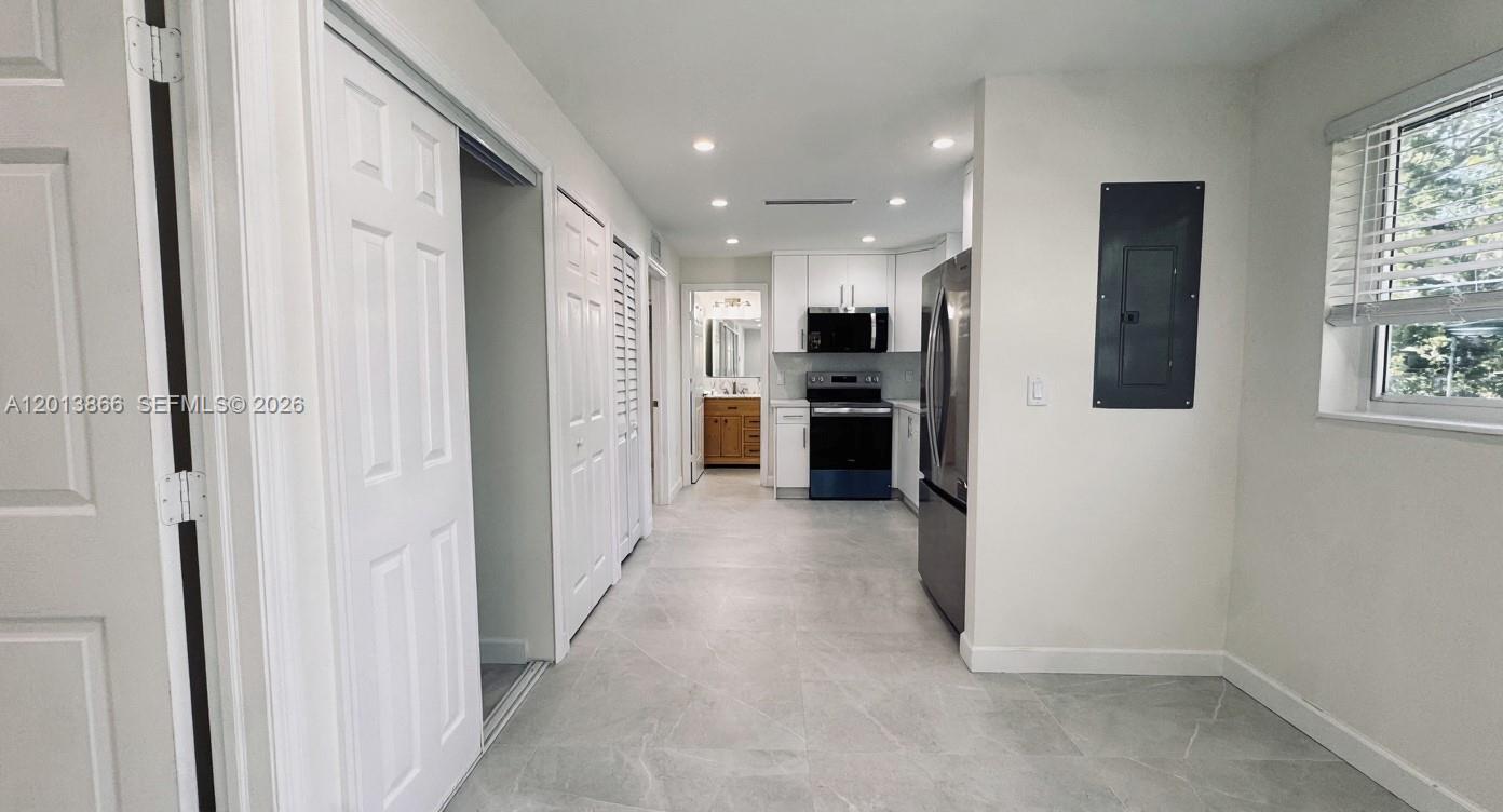 8440 Southwest 107th Street, Unit GH Miami, FL 33156 - Photo 1 of 22 a view of a hallway with wooden shelves and kitchen