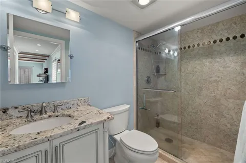 a bathroom with a granite countertop sink toilet and shower