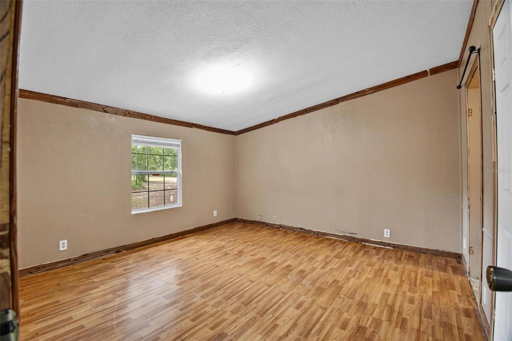 156 Kingfish Road Pomona Park, FL 32181 - Photo 18 of 55 a view of an empty room with wooden floor and a window