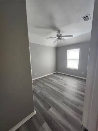 an empty room with windows and fan