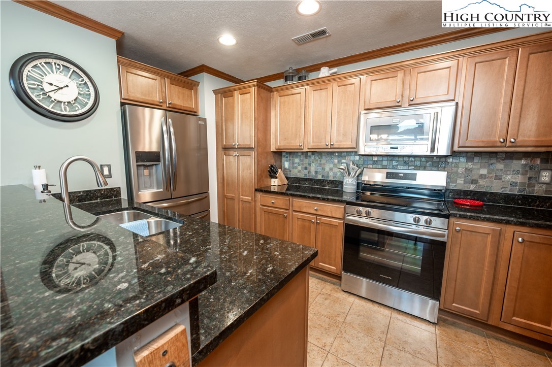 342 Ridgeline Drive, Unit 15B Sugar Mountain, NC 28604 - Photo 23 of 26 a kitchen with kitchen island granite countertop a stove a sink and a refrigerator