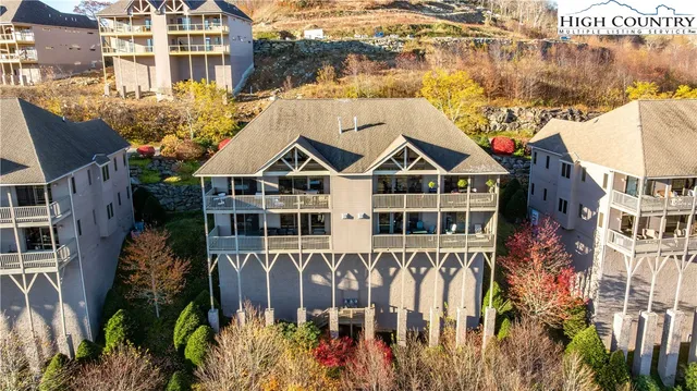 a view of a blue and white house with large windows and plants