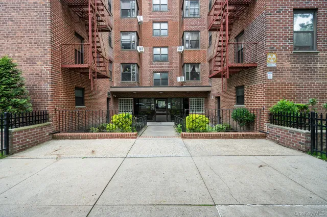 front view of a brick house with a small yard and potted plants