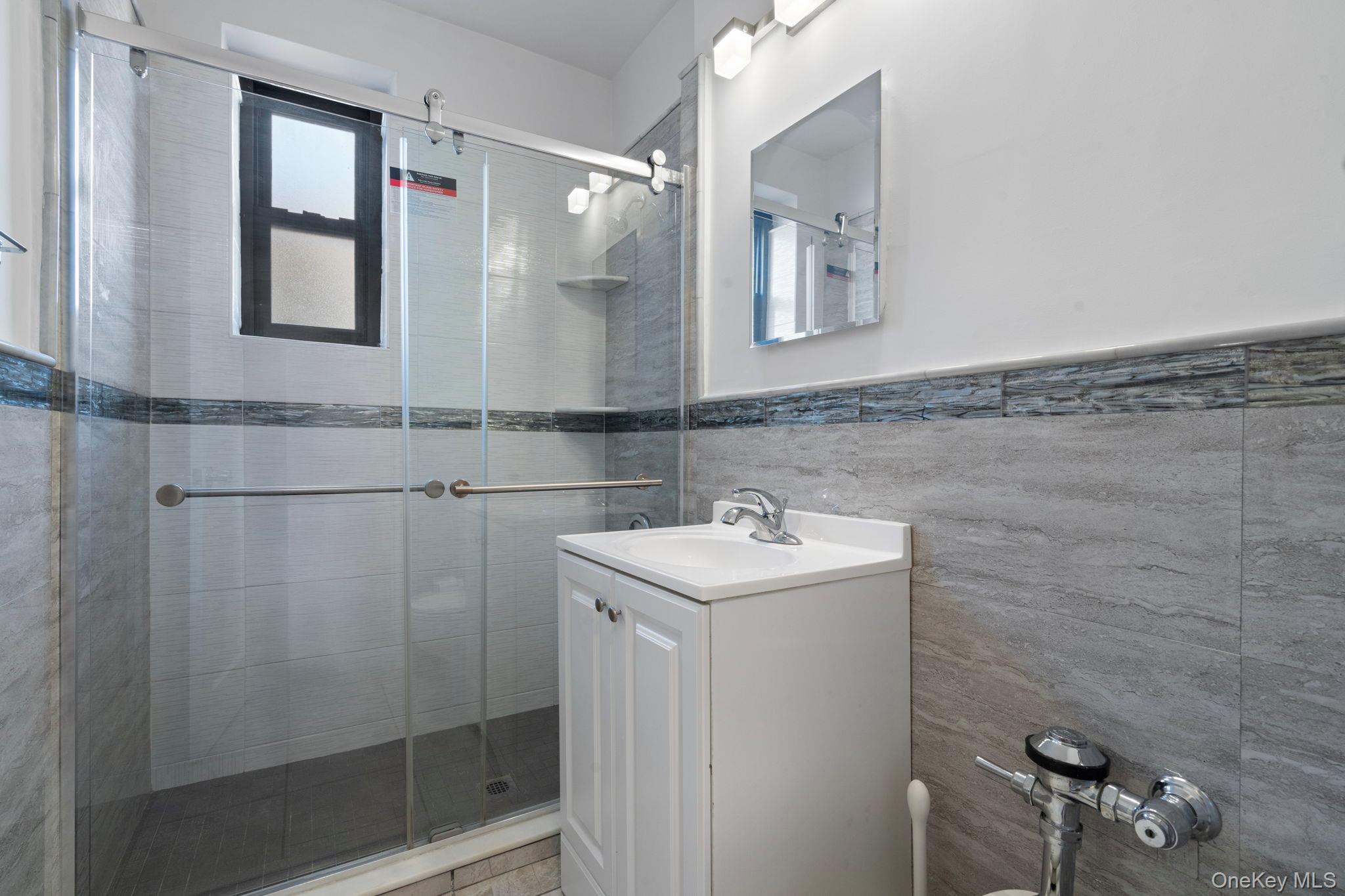 32-40 89th Street, Unit C409 Queens, NY 11369 - Photo 15 of 32 a bathroom with a sink a mirror and shower