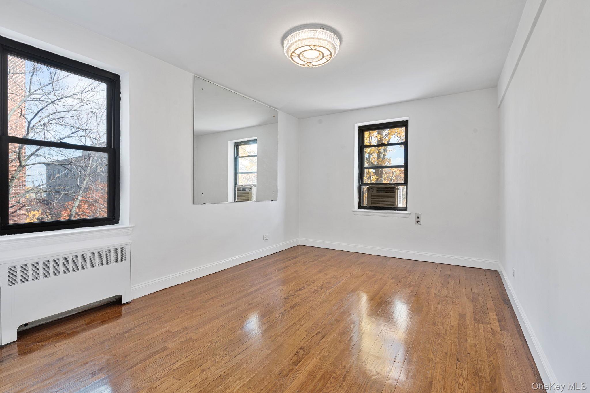 32-40 89th Street, Unit C409 Queens, NY 11369 - Photo 17 of 32 an empty room with wooden floor and windows