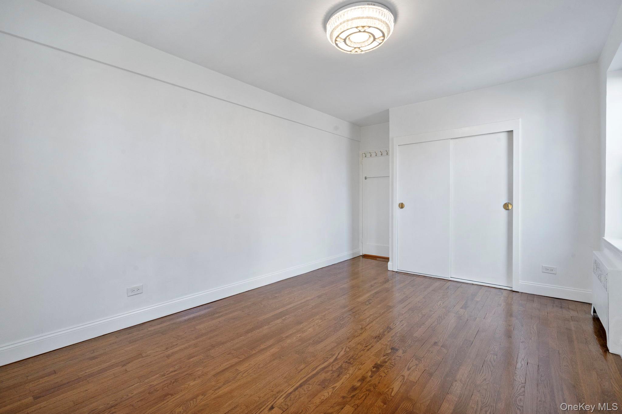 32-40 89th Street, Unit C409 Queens, NY 11369 - Photo 19 of 32 a view of an empty room with wooden floor and a window