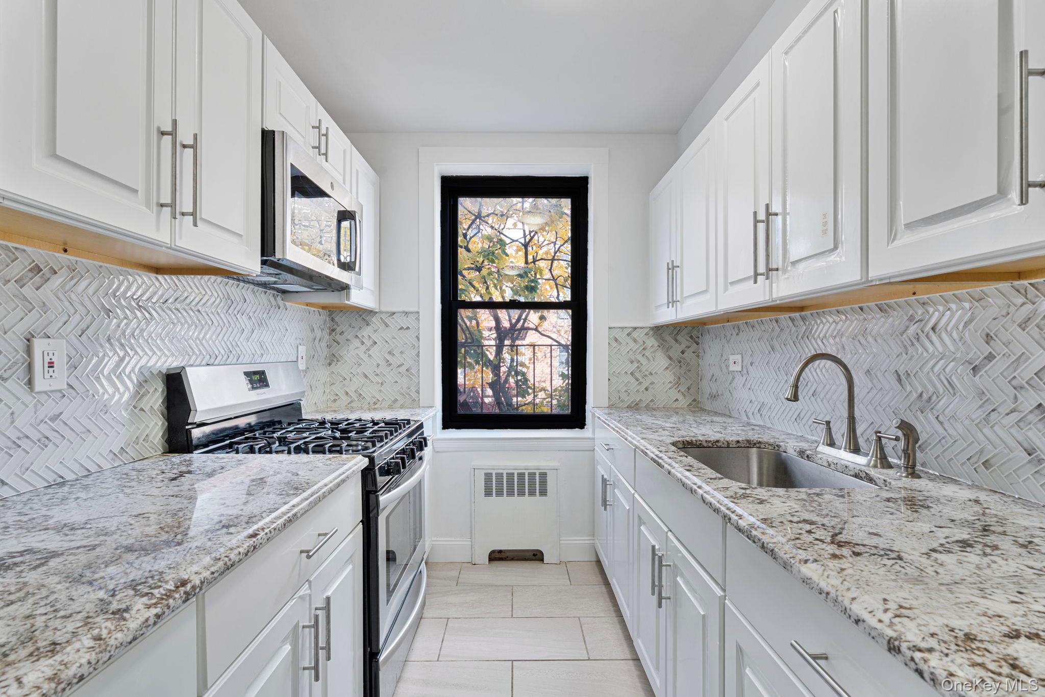 32-40 89th Street, Unit C409 Queens, NY 11369 - Photo 22 of 32 a kitchen with stainless steel appliances granite countertop a sink stove and cabinets
