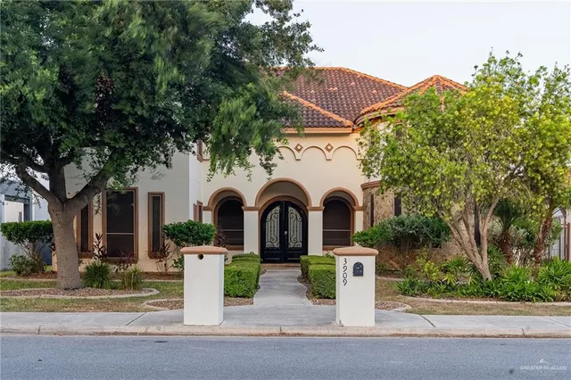 a front view of a house with garden and trees