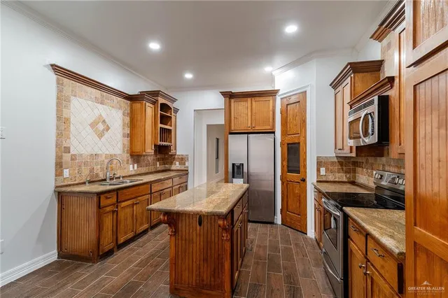 a kitchen with stainless steel appliances kitchen island granite countertop a stove refrigerator and cabinets