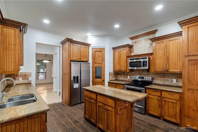 a kitchen with stainless steel appliances granite countertop a stove a sink dishwasher a refrigerator and a microwave oven with wooden floor