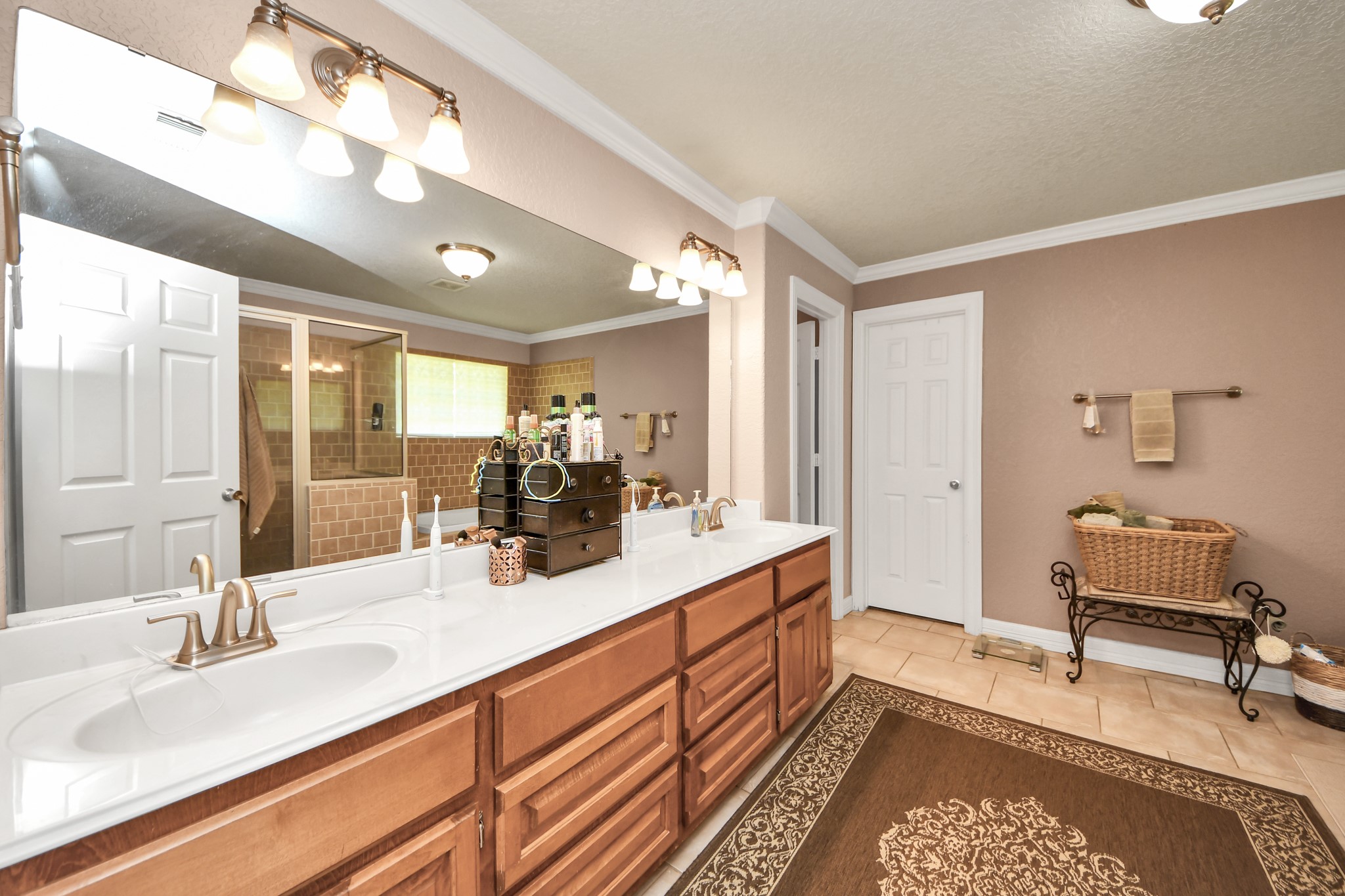 1102 West Point Drive Rosharon, TX 77583 - Photo 9 of 39 Spacious bathroom with dual sinks, elegant lighting, and a large mirror. Features a walk-in shower, ample storage, and warm, neutral tones for a relaxing atmosphere.