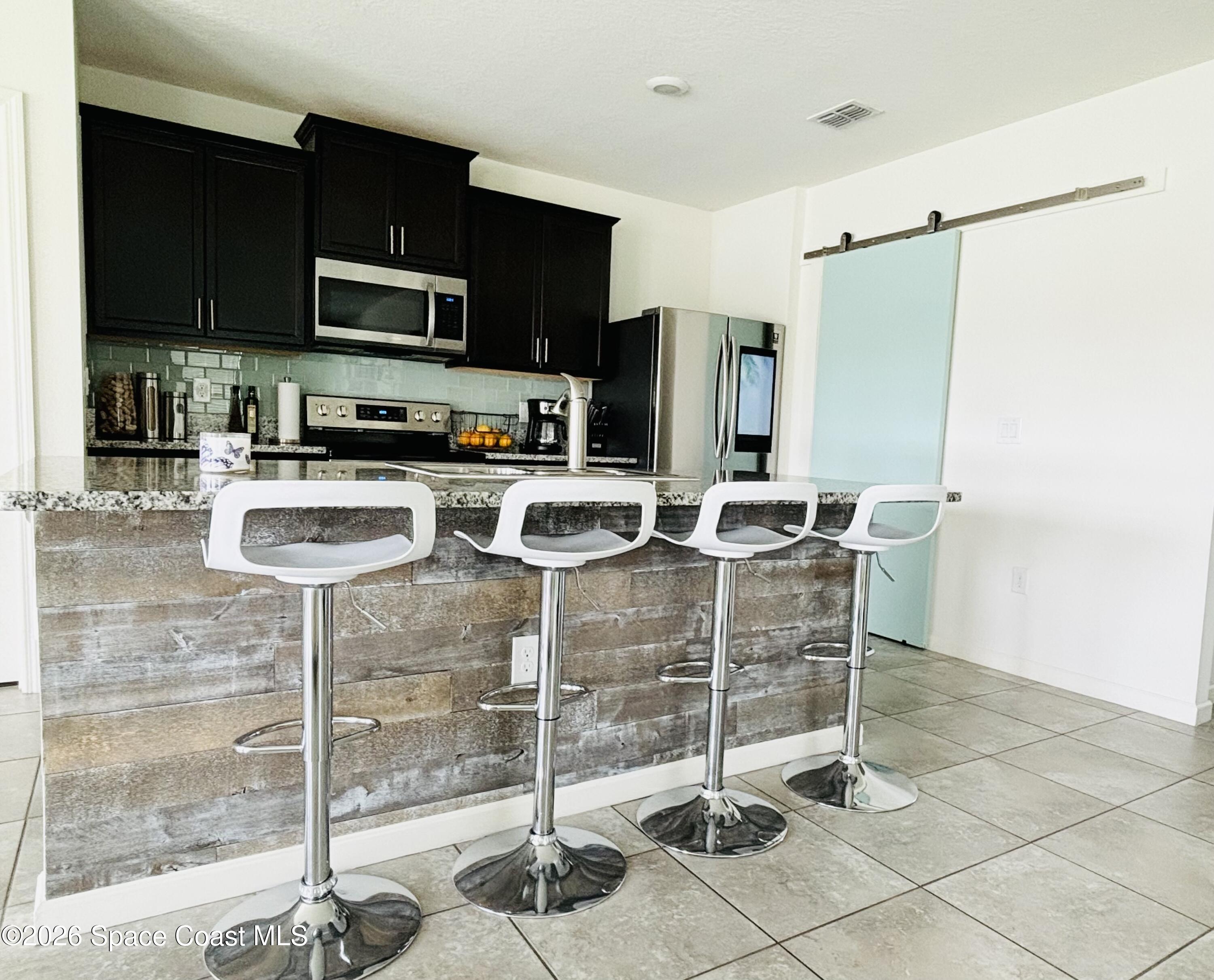 841 Old Country Rd S East Palm Bay, FL 32909 - Photo 2 of 16 a kitchen with granite countertop a refrigerator a stove top oven and a sink