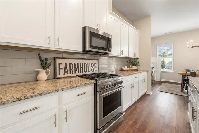 a kitchen with granite countertop a stove a sink and a microwave
