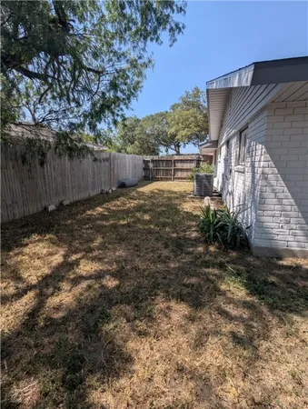 a view of backyard with wooden fence and large trees