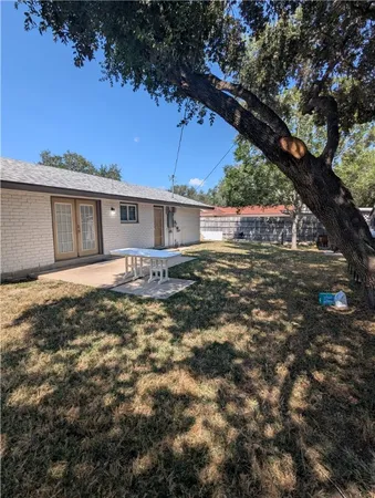 a backyard of a house with table and chairs under an umbrella