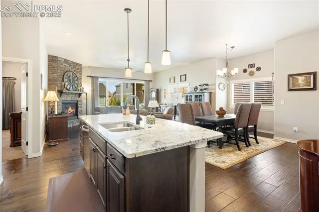 a kitchen with stainless steel appliances kitchen island granite countertop a table chairs and a refrigerator