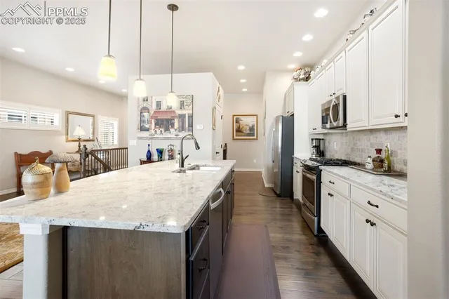 a kitchen with stainless steel appliances kitchen island granite countertop a sink a stove and a wooden floors
