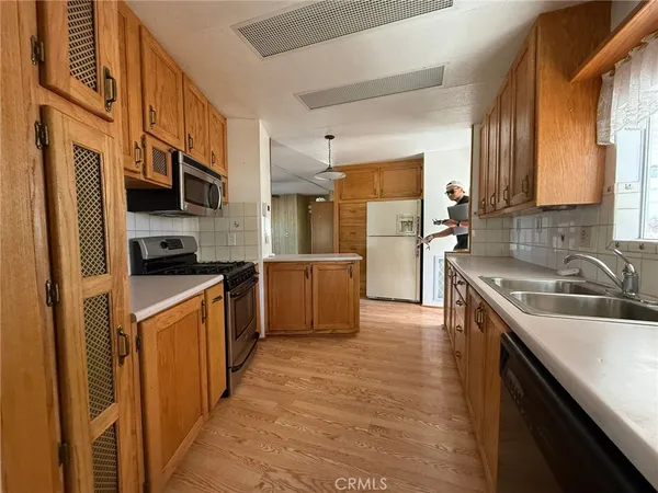 a kitchen with stainless steel appliances granite countertop a sink a stove top oven a refrigerator cabinets and a kitchen island