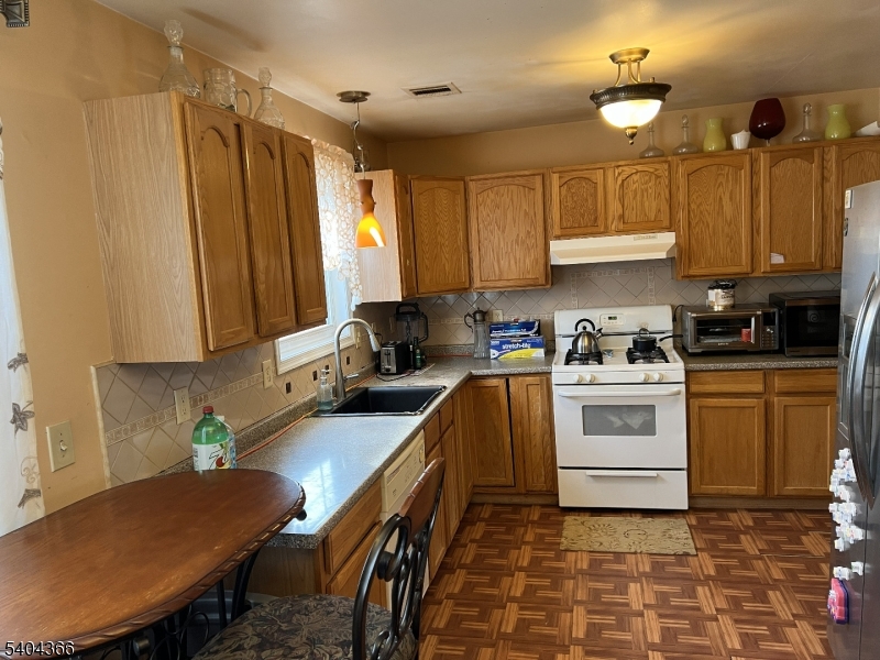 415 Wheatsheaf Road Roselle, NJ 07203 - Photo 17 of 30 a kitchen with a stove a sink a refrigerator and cabinets
