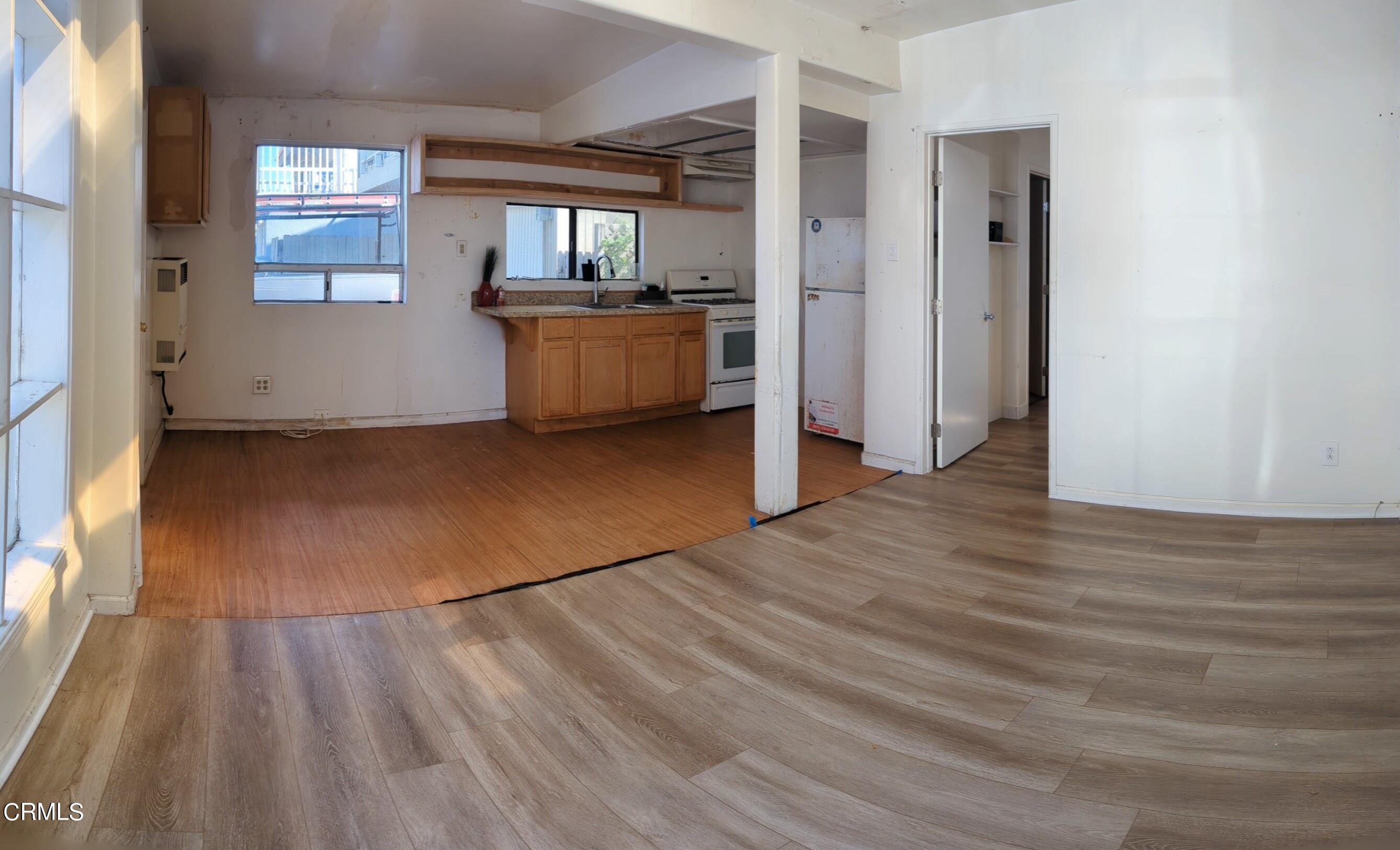 a view of empty room with kitchen and window