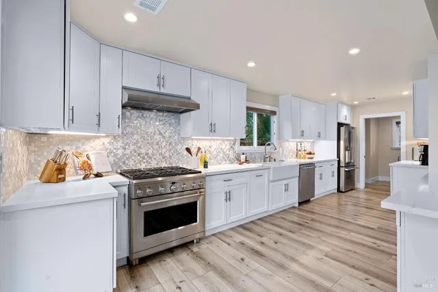 a kitchen with stainless steel appliances white cabinets sink and stove top oven
