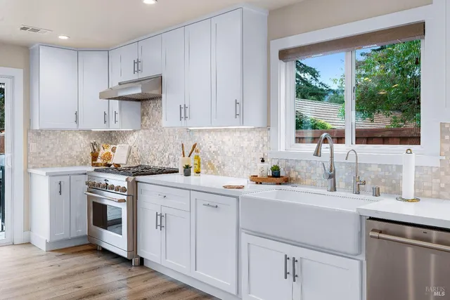 a kitchen with a sink white cabinets and white appliances