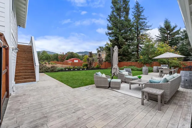 a view of a patio with couches and table and chairs with wooden fence and plants