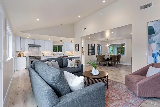 a living room with furniture kitchen view and a wooden floor