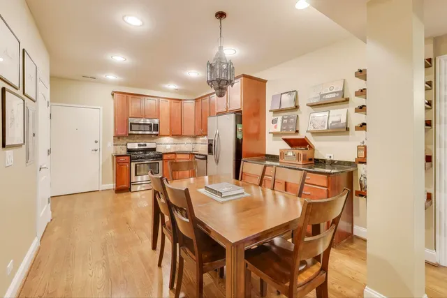 a kitchen with stainless steel appliances kitchen island granite countertop a dining table chairs and refrigerator