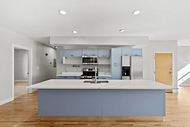 a large white kitchen with kitchen island a sink stainless steel appliances and cabinets