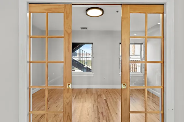 a view of an empty room with wooden floor and a window