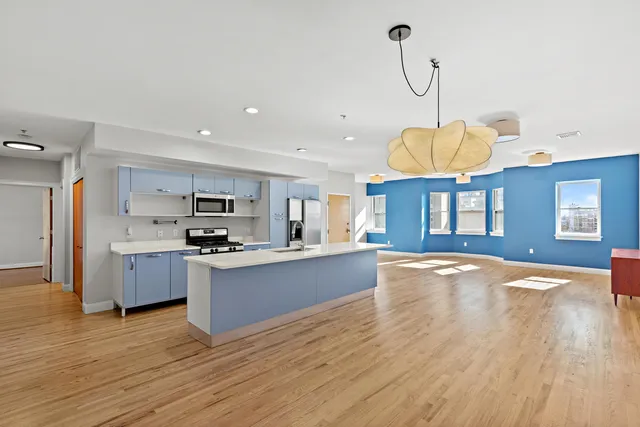 a large kitchen with stainless steel appliances granite countertop a sink a stove a dining table and chairs with wooden floor