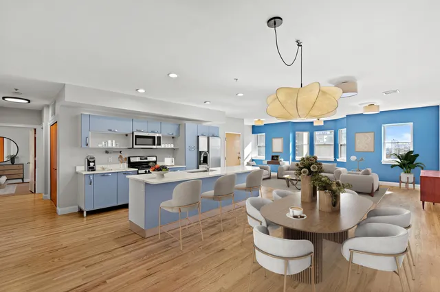 a living room with stainless steel appliances kitchen island granite countertop a stove a kitchen island a dining table and chairs with wooden floor